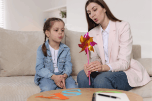 Speech therapist working with little girl indoors